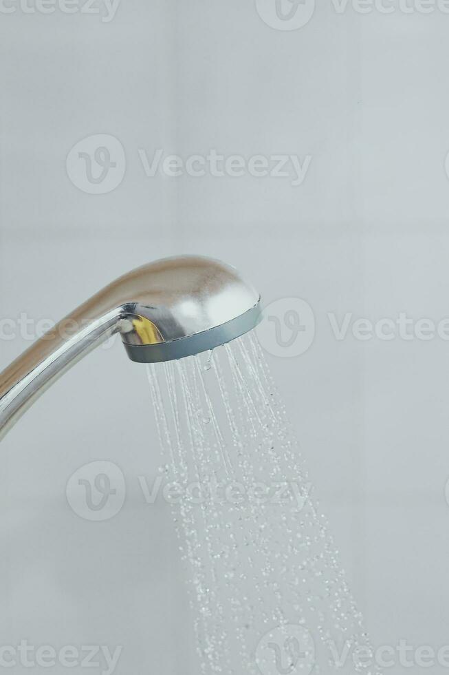 alcachofa de la ducha con fluido agua. agua corriendo desde el cabeza de el ducha en el bañera foto