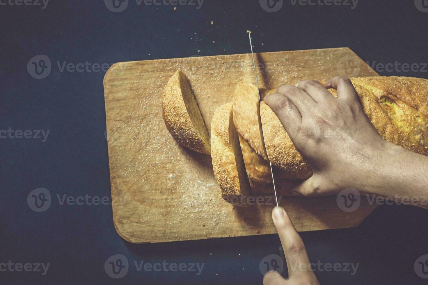 Food concept. Hand cutting bread. Slicing a bread. Top view. photo