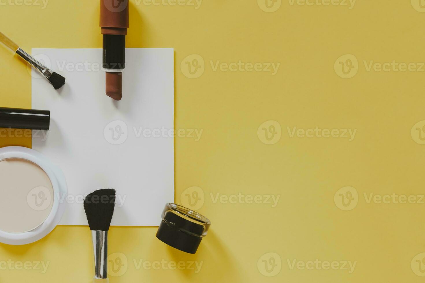 Women's cosmetics and accessories and white paper on a yellow background. Beauty products. View from above. Copy space photo