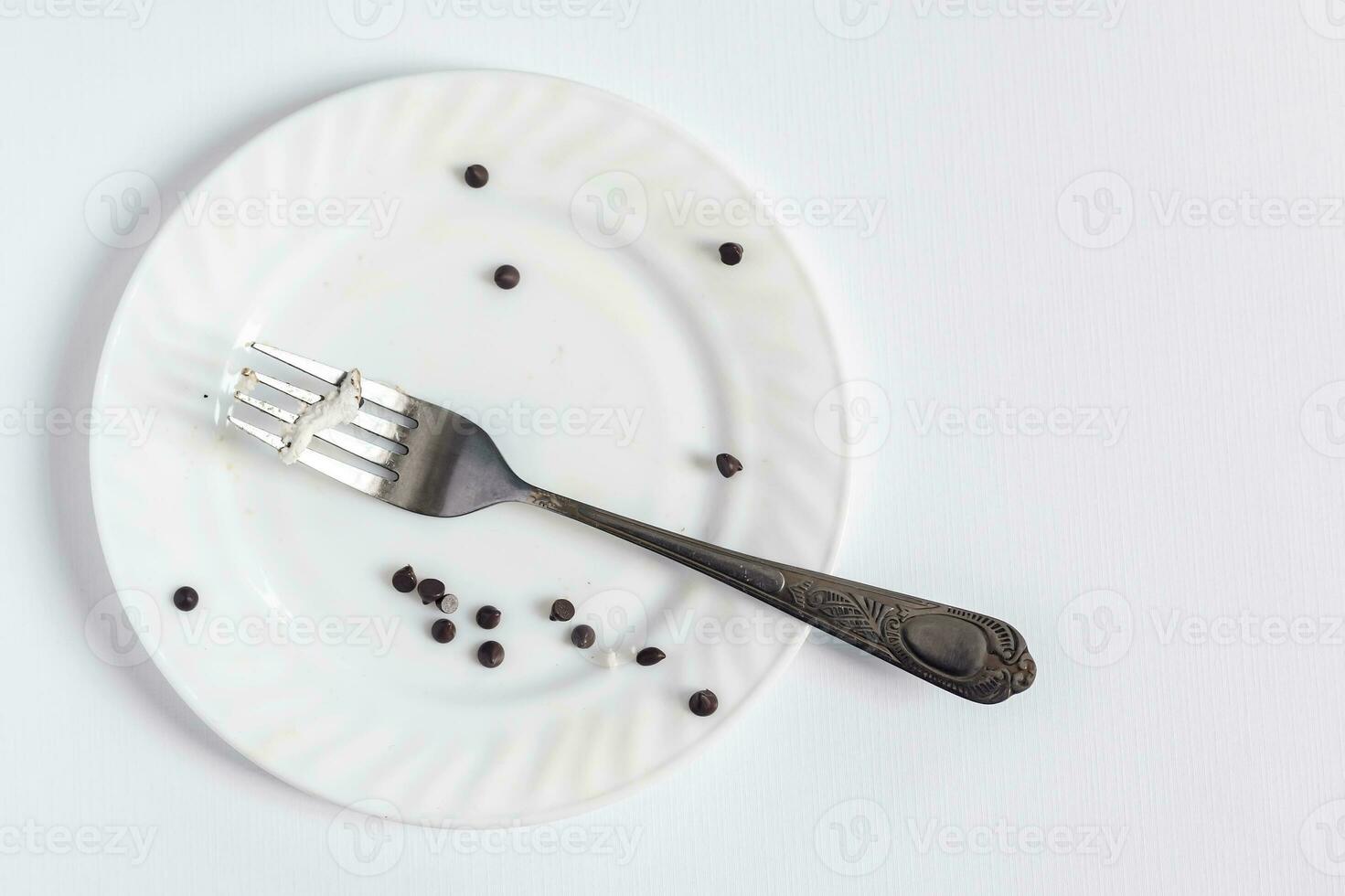 Empty dirty white plate and fork on the white background. Dirty plate with pieces and crumbs dessert photo