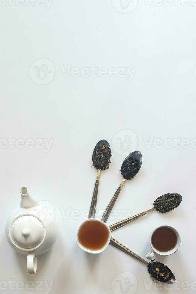 Tea set with white ceramic tea pot and other tea ingredients on the white. Flat lay view of various dried teas and teapot. View from above. Space for your text photo