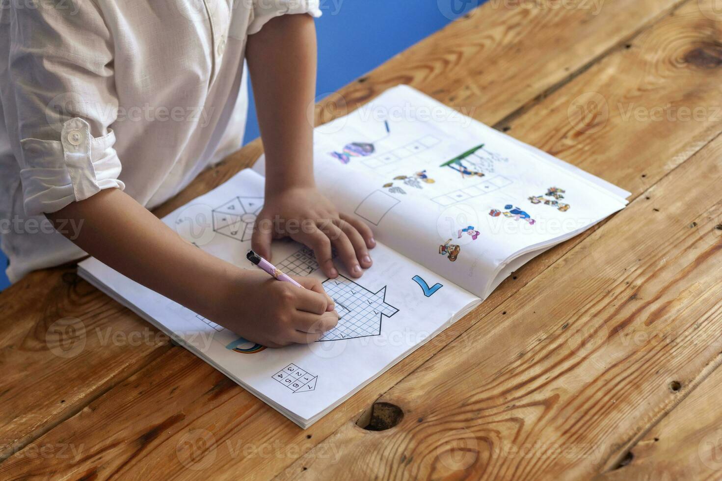 Preschool age child doing the math. Little boy doing homework. Drawing on kid notepad. Free space photo