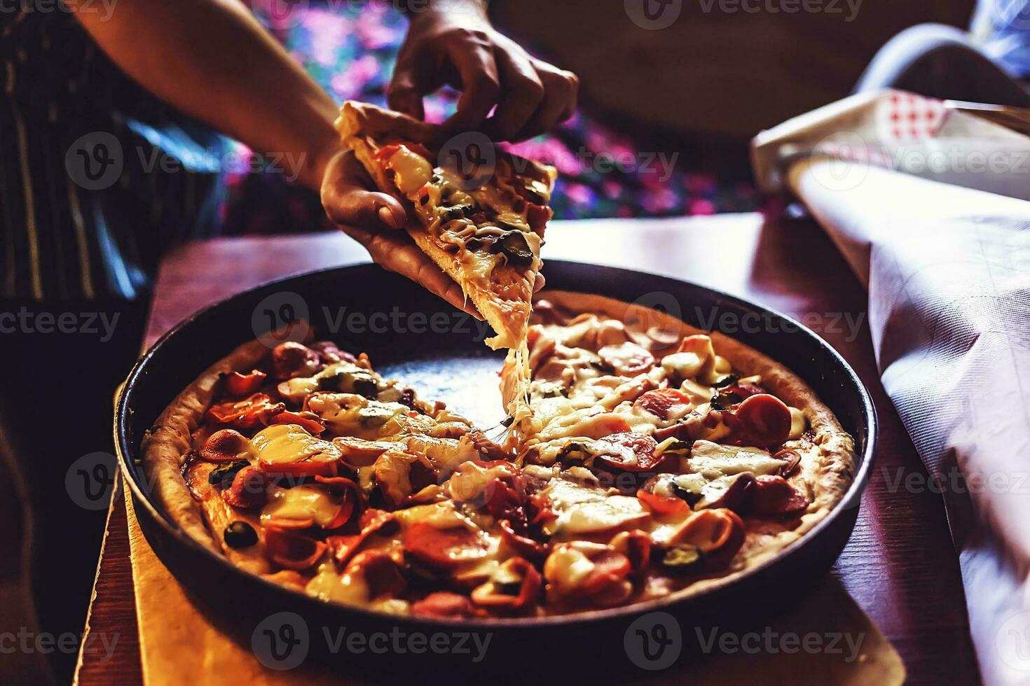 Person's hand taking a piece of pizza photo