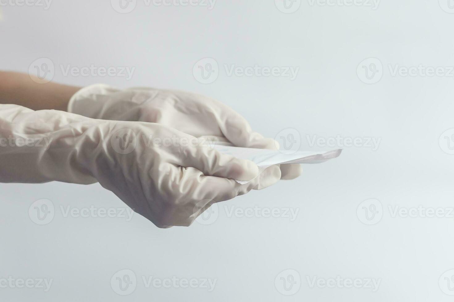 Female's hygiene products. Woman's hands in medical gloves holding sanitary napkins against white background. Period days concept showing feminine menstrual cycle. photo