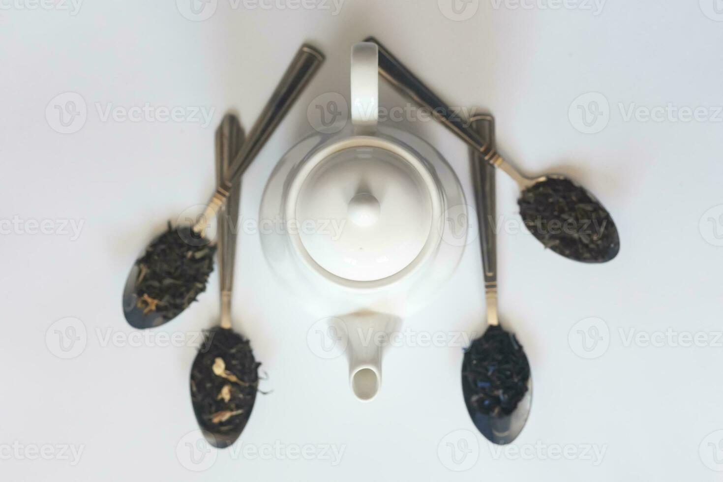 White ceramic tea pot and various dried teas on the white background. Flat lay view. Space for your text photo