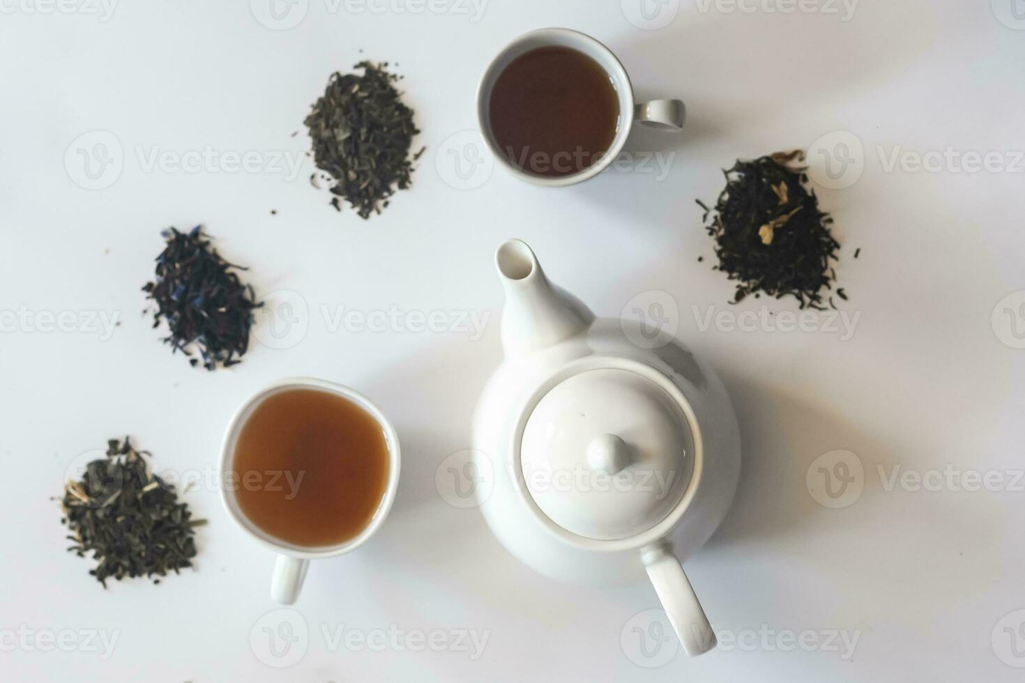 Tea set with white ceramic tea pot and other tea ingredients on the white. Flat lay view of various dried teas and teapot. View from above. Space for your text photo