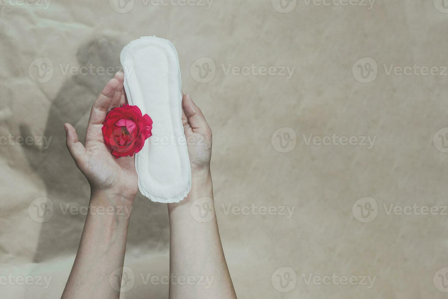 Female's hand holding sanitary napkins with red rose on it. Period days concept showing feminine menstrual cycle photo