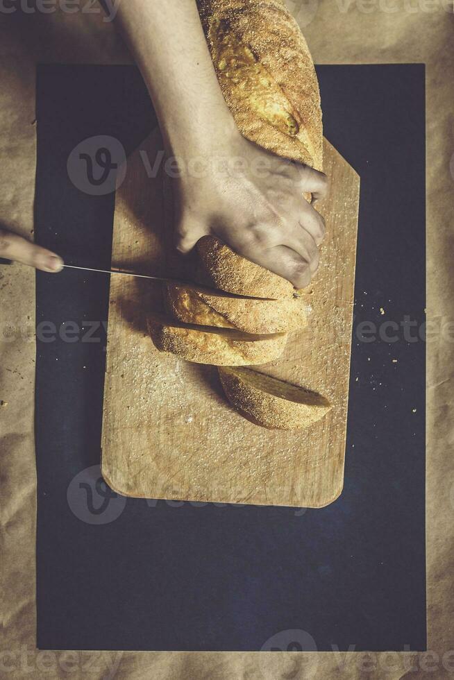 comida concepto. mano corte un pan. rebanar un un pan. parte superior vista. foto