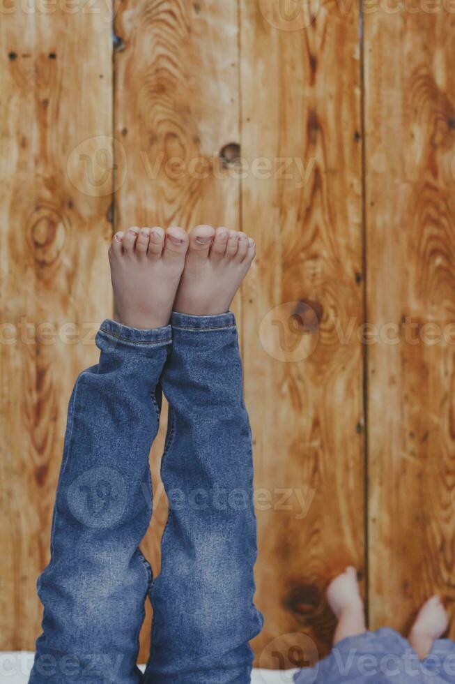 dos joven hermanos acostado en su cama. niños teniendo divertida. dos pequeño hermanos levantamiento su piernas en contra el de madera escritorio. foto