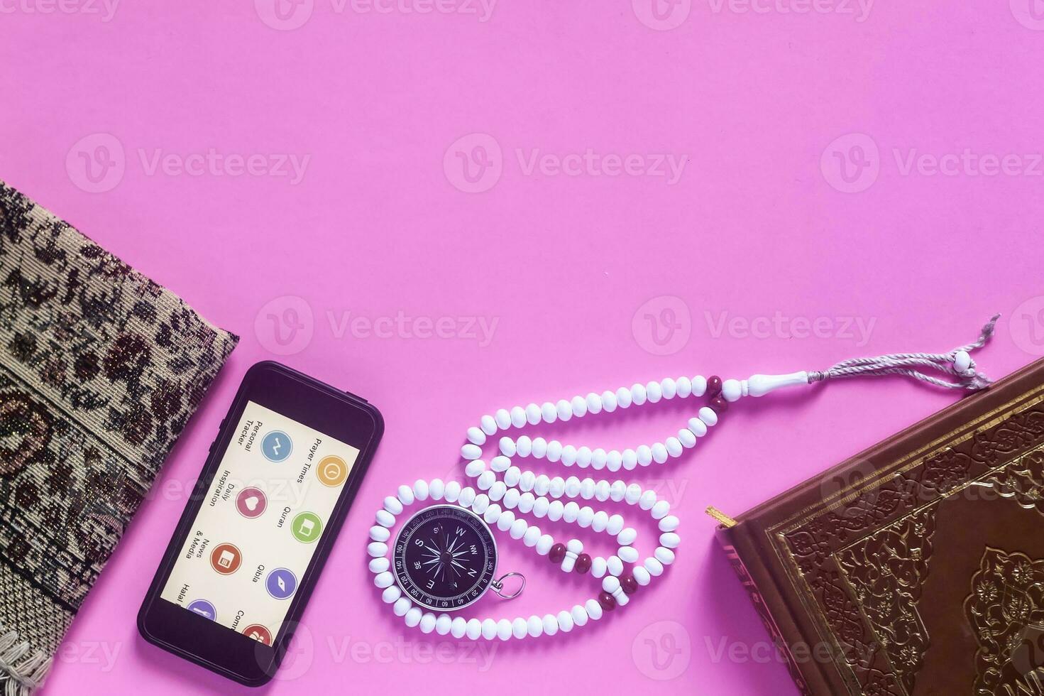 Traditional muslim prayer set bundle. Praying carpet, rosary beads, little version of the Holy Quran and qibla compass on wooden background. Free Space photo