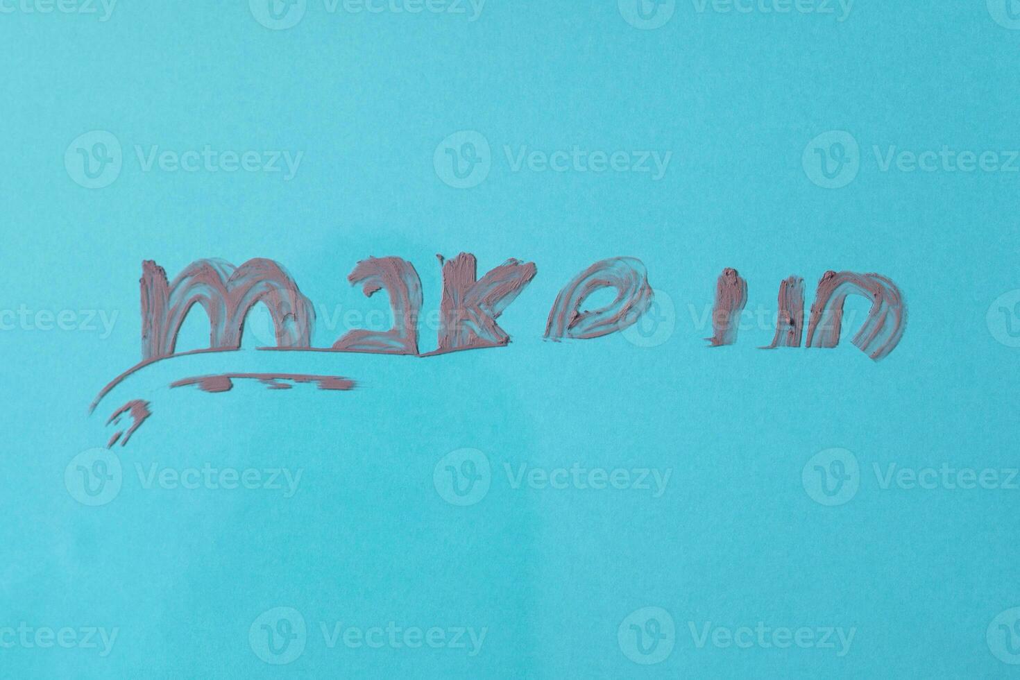 The word make up written with lipstick on blue background photo