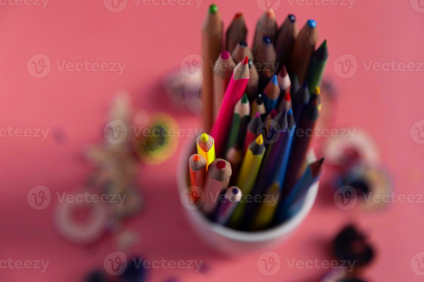 Stack of colorful pencils and shaves around it photo