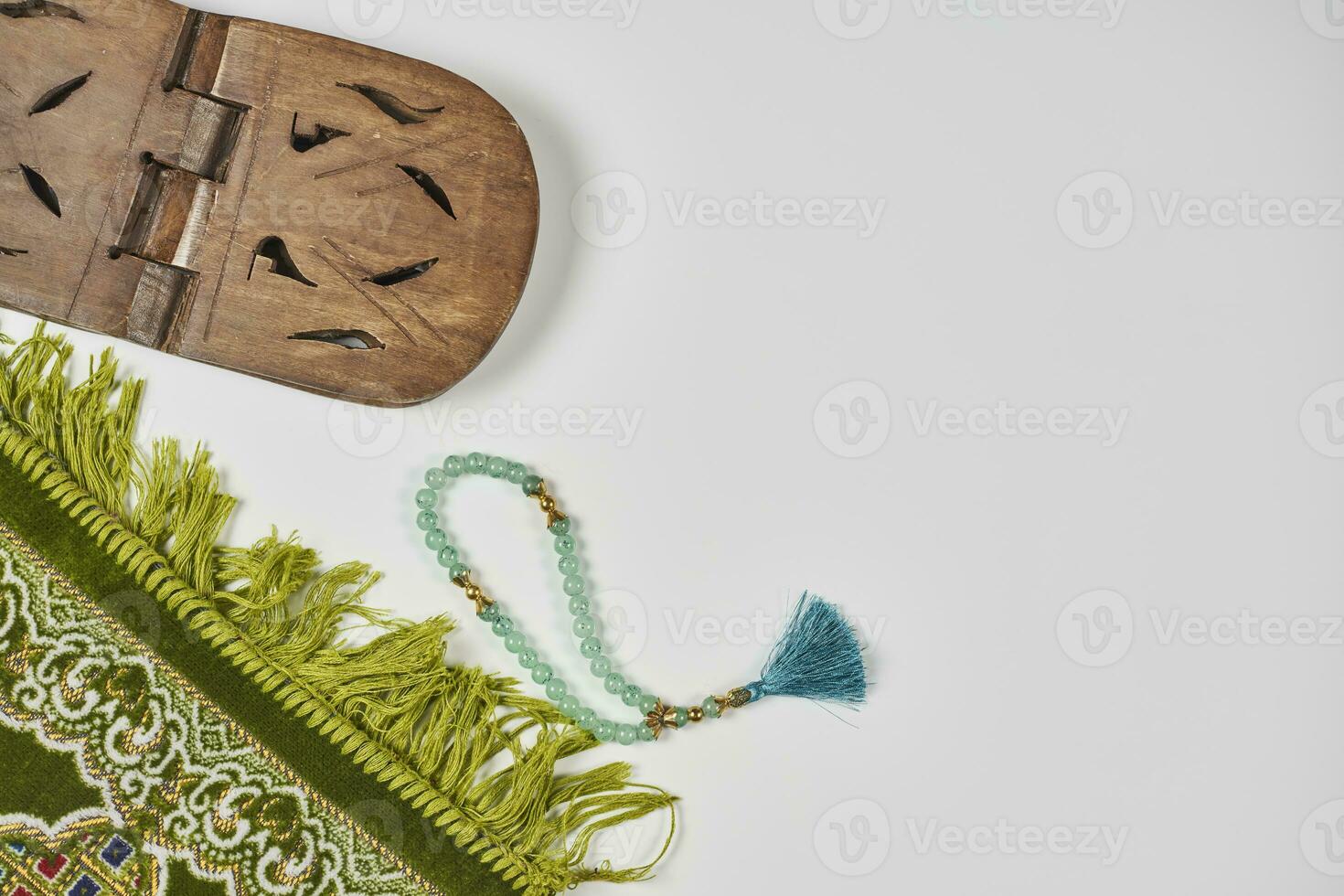 Islamic praying carpet, wooden Quran book stand holder and praying beads on white photo