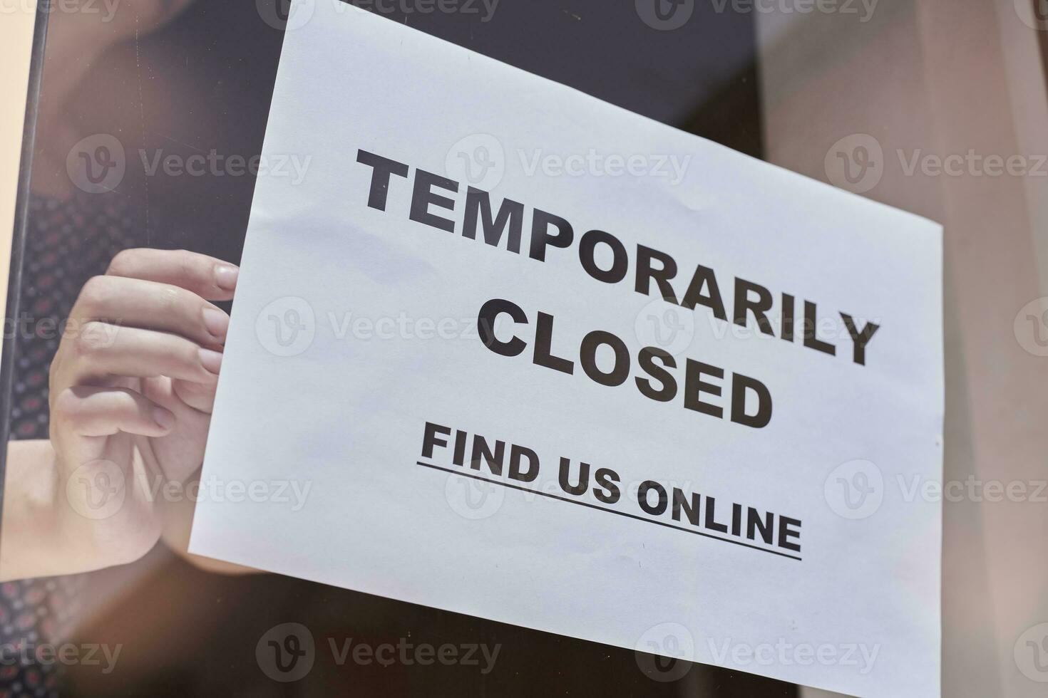 Shop or restaurant worker hanging closed sign photo