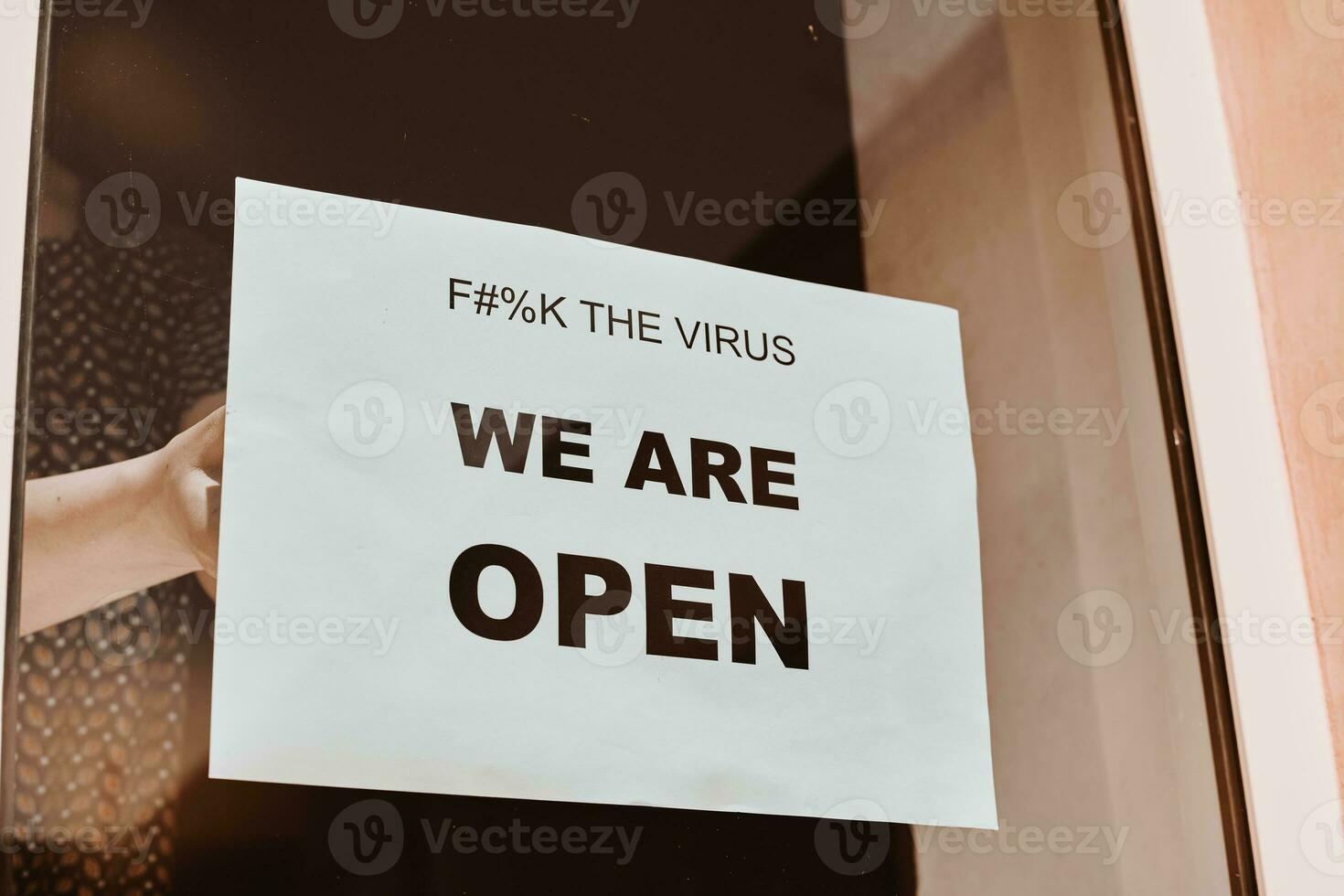 Shop or restaurant worker hanging a paper sign photo