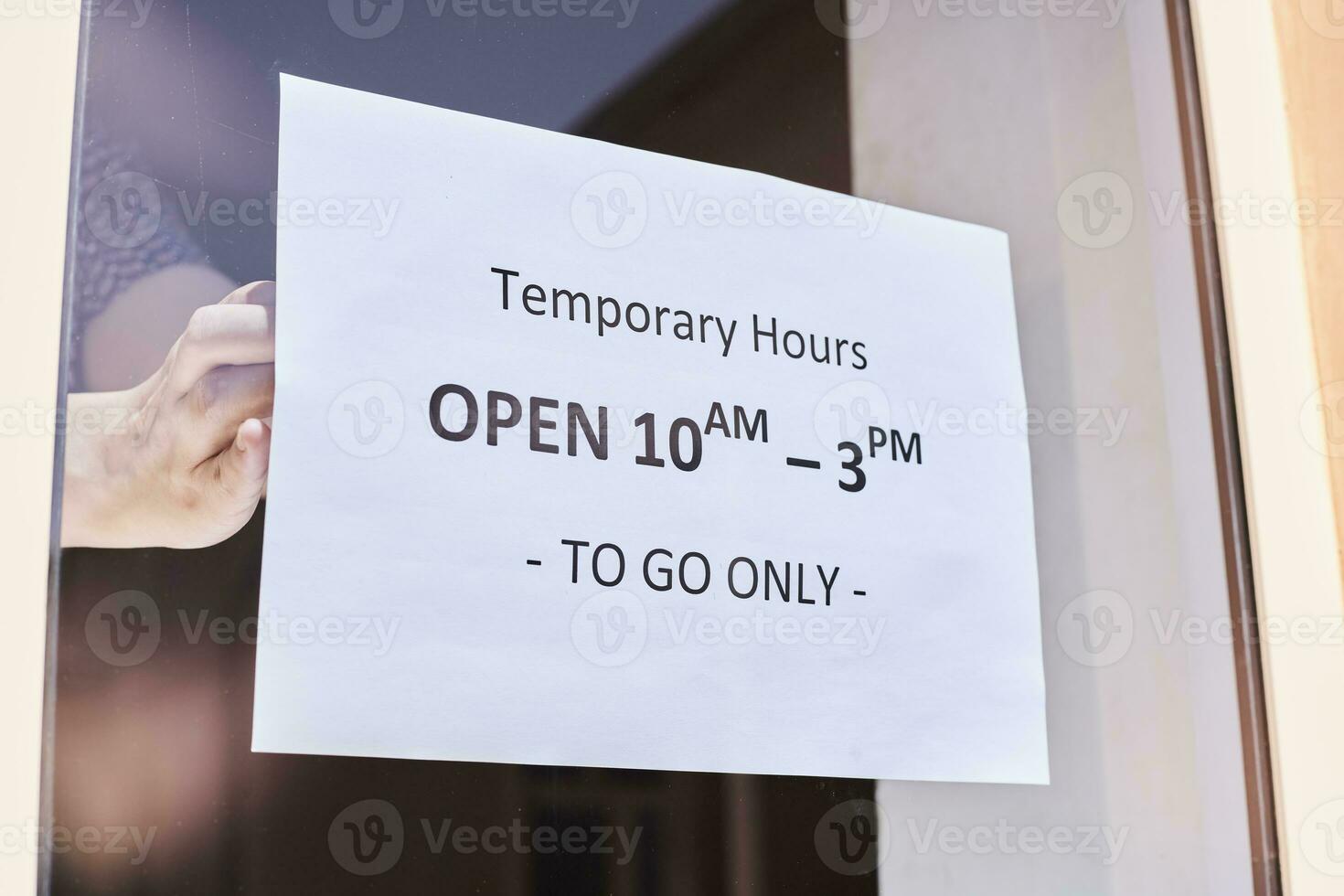 Shop or restaurant worker hanging a warning sign photo