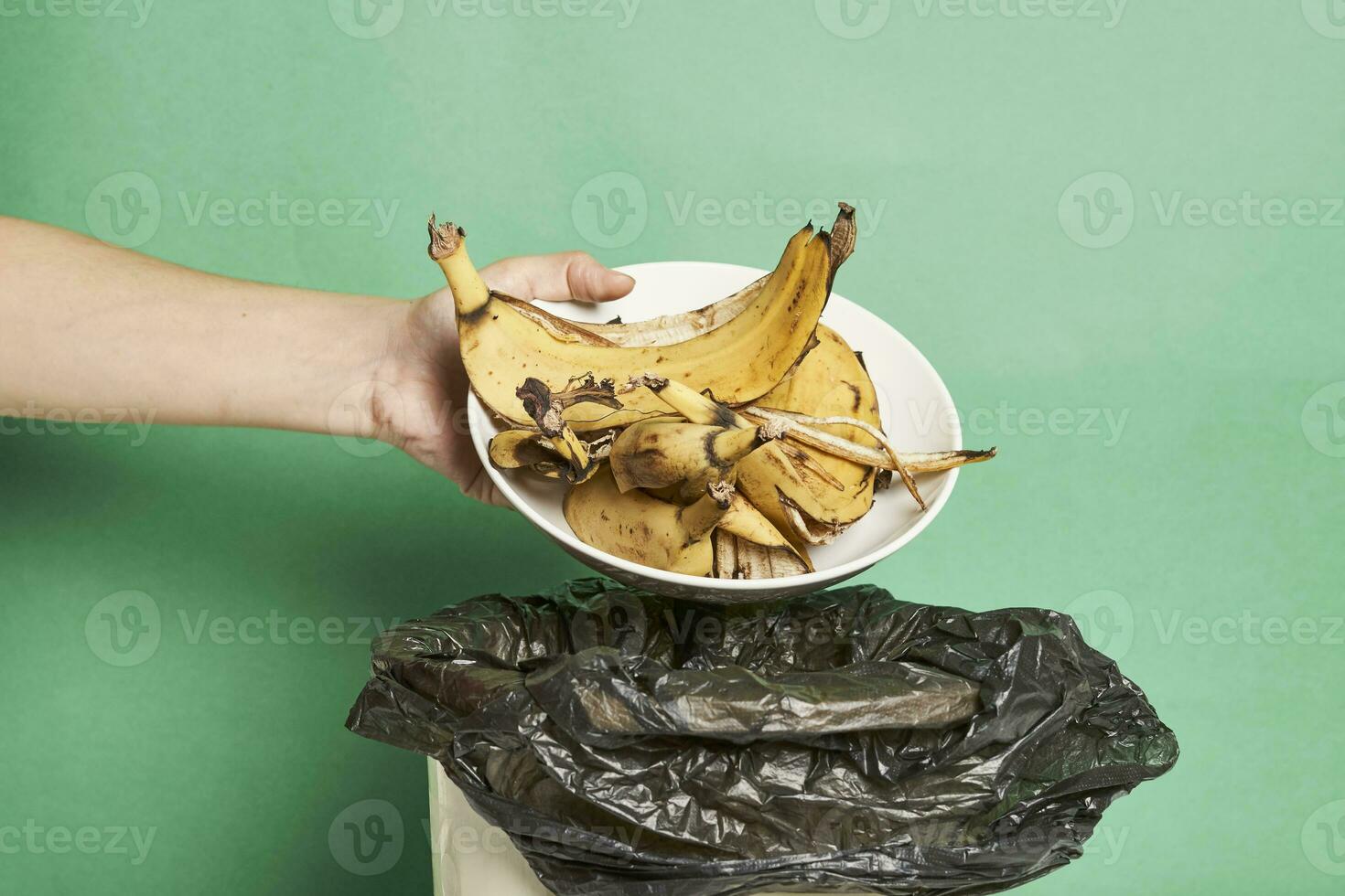 Woman thorwing banana peels in trash can photo