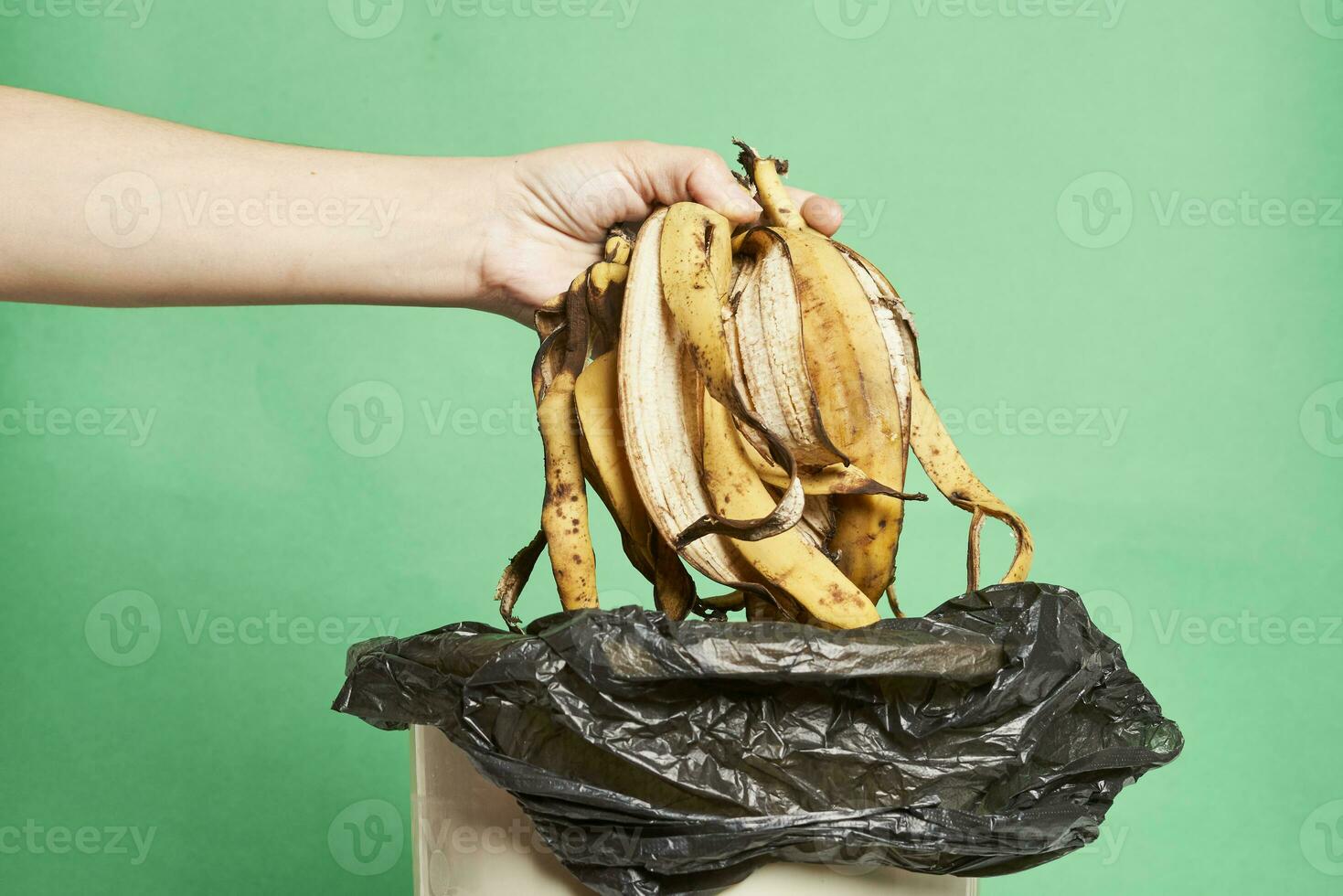 mujer lanzando plátano pela en basura lata foto