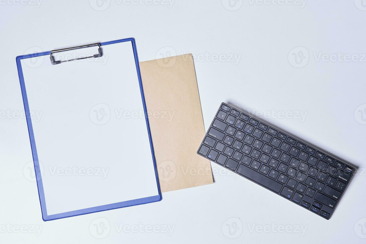 Empty clipboard with white paper, envelope and keyboard photo