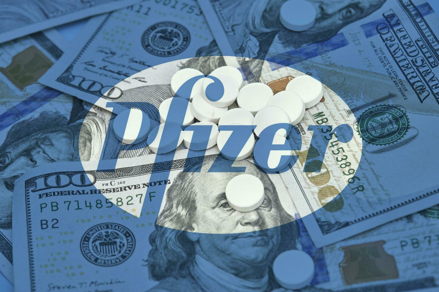 Pile of us dollars and white tablets with Pfizer logo photo