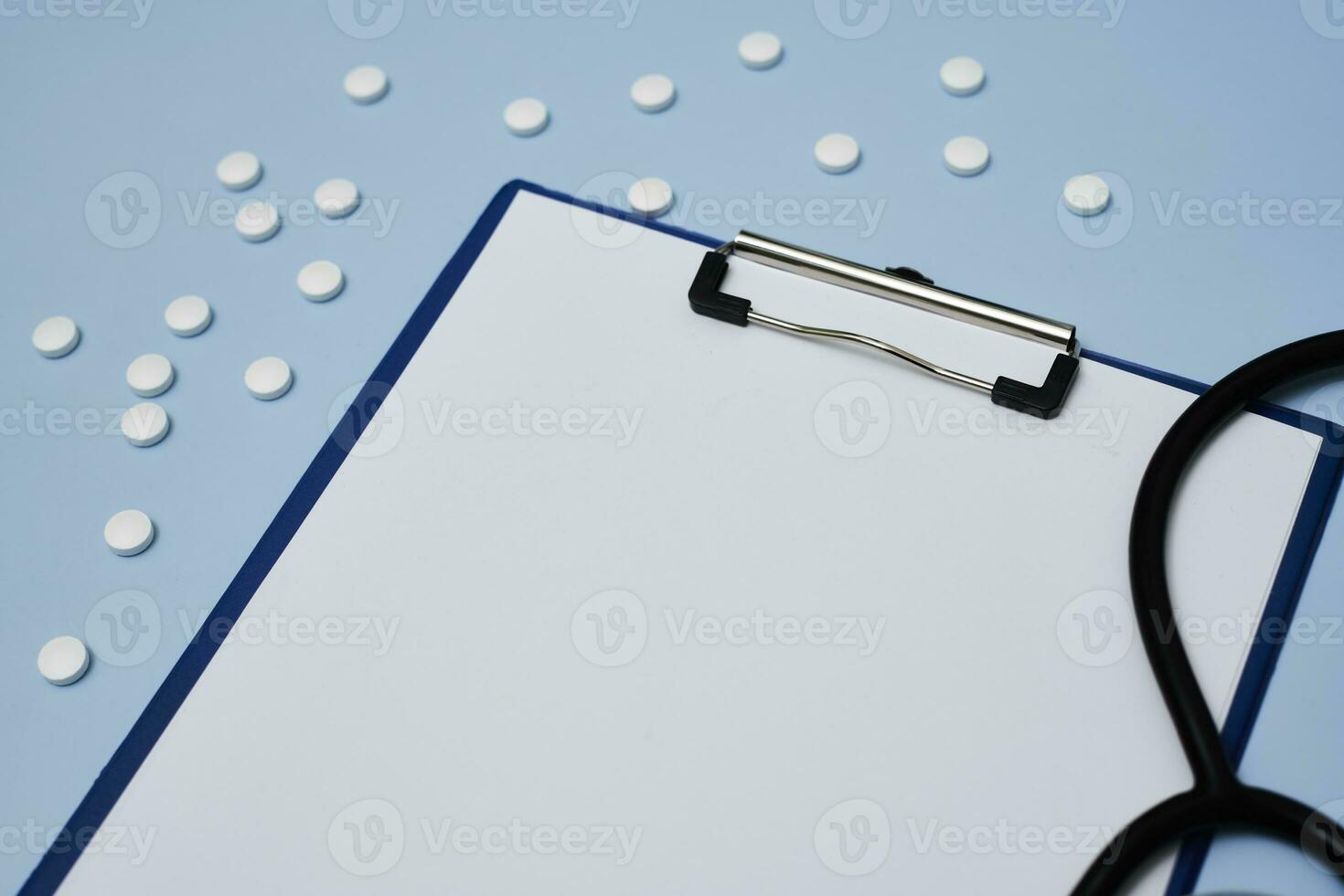 A clipboard with blank paper, medical pills and stethoscope photo