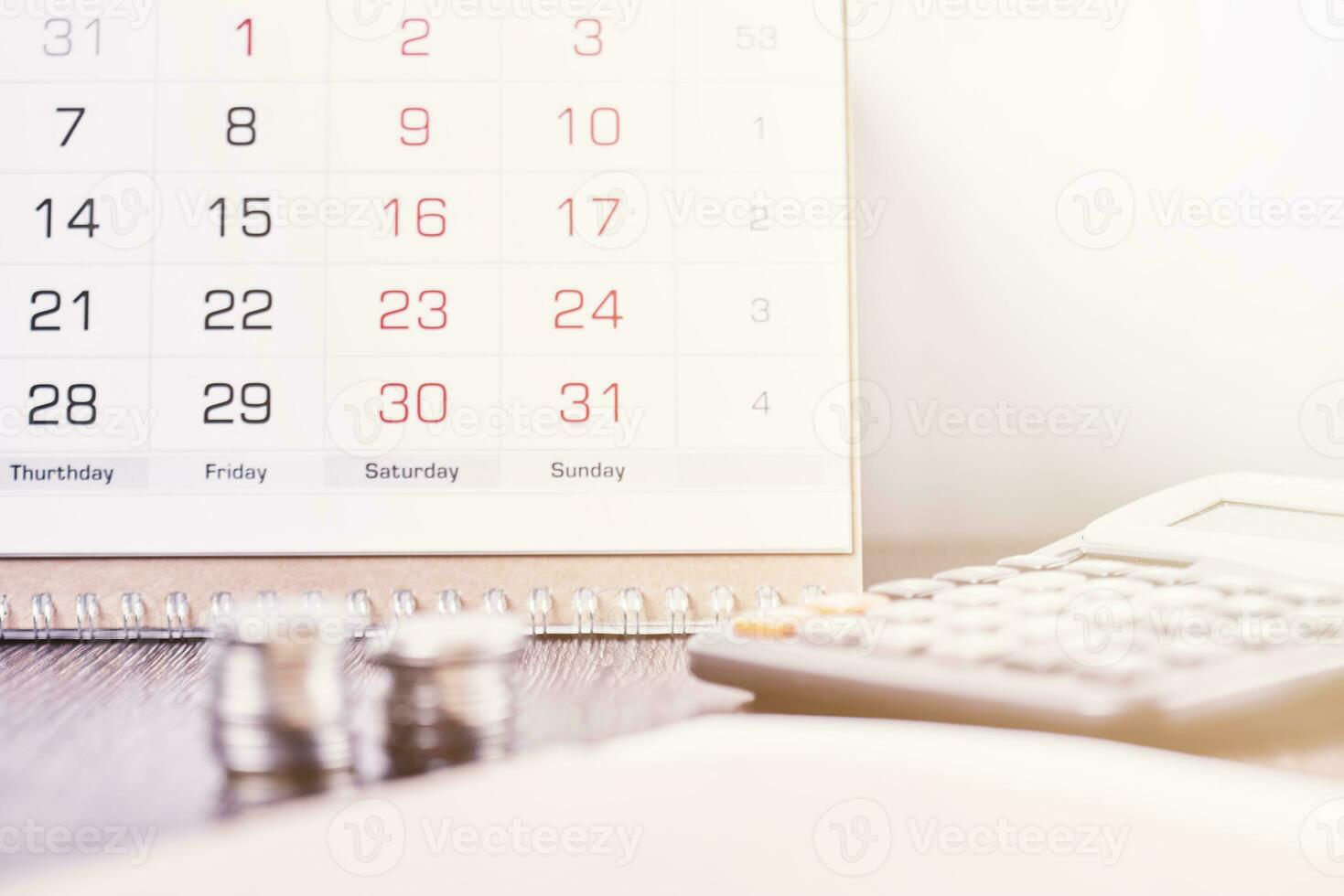 calendario, calculadora y apilar de monedas en oficina foto