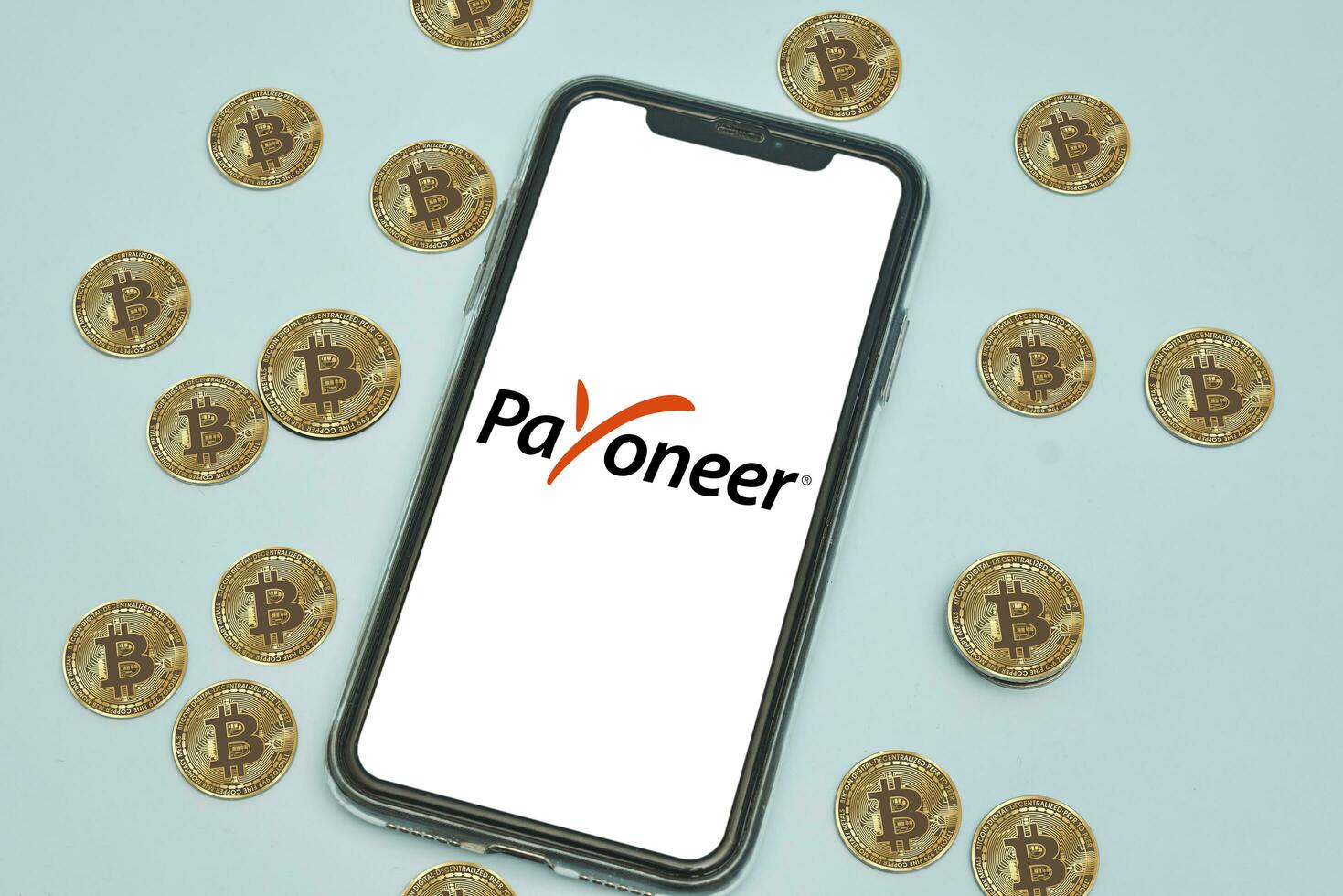 Payoneer logo app on mobile phone screen and bitcoins cryptocurrency photo