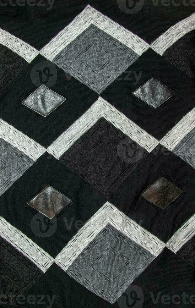 Detailed inserts in black genuine leather on a knitted woolen background with an abstract pattern. Abstract fabric texture. photo