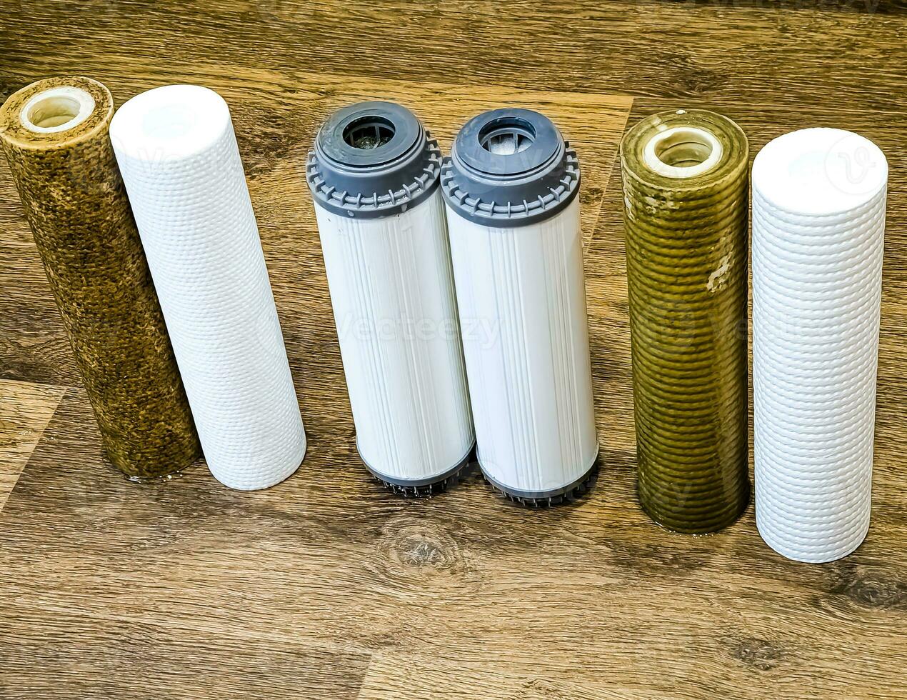 Used water filters with traces of dirt, clay and impurities and clean filters, prepared for replacement. Replacing multi-stage water filter cartridges. photo