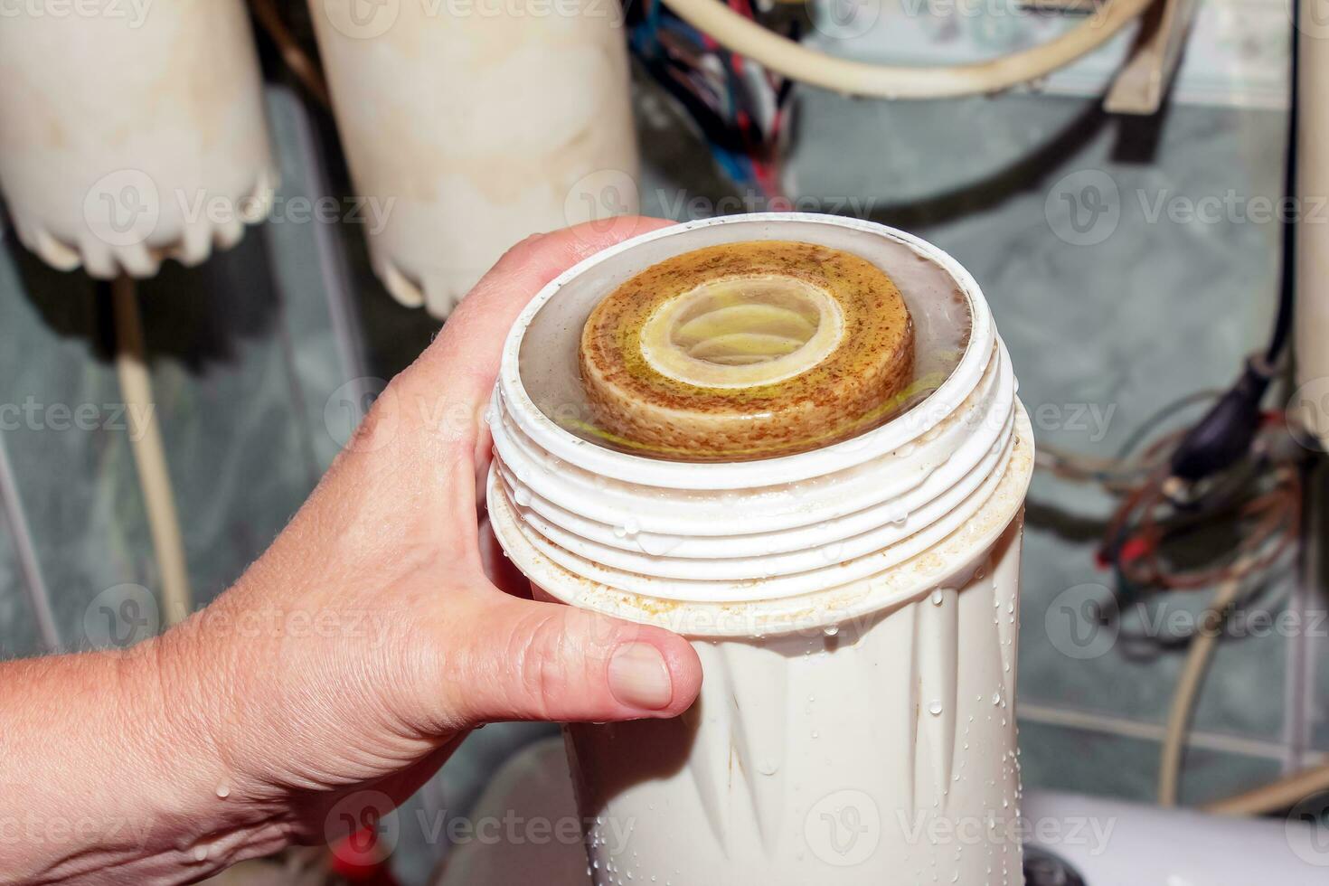 Women's hands remove flasks with contaminated water purification filters to be replaced with clean ones. The process of replacing the cartridges of a multi-stage water filter. photo