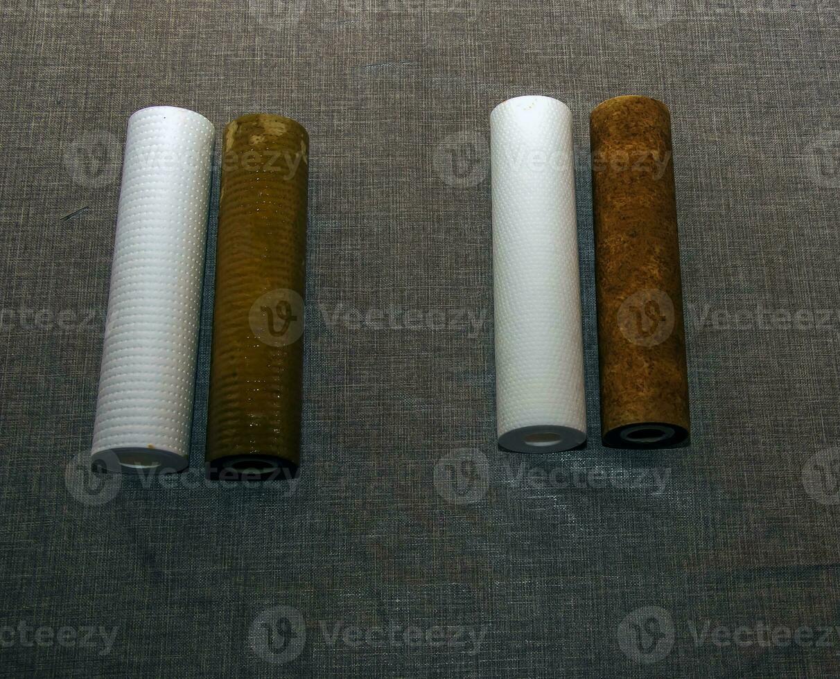 Used water filters with traces of dirt, clay and impurities and clean filters, prepared for replacement. Replacing multi-stage water filter cartridges. photo