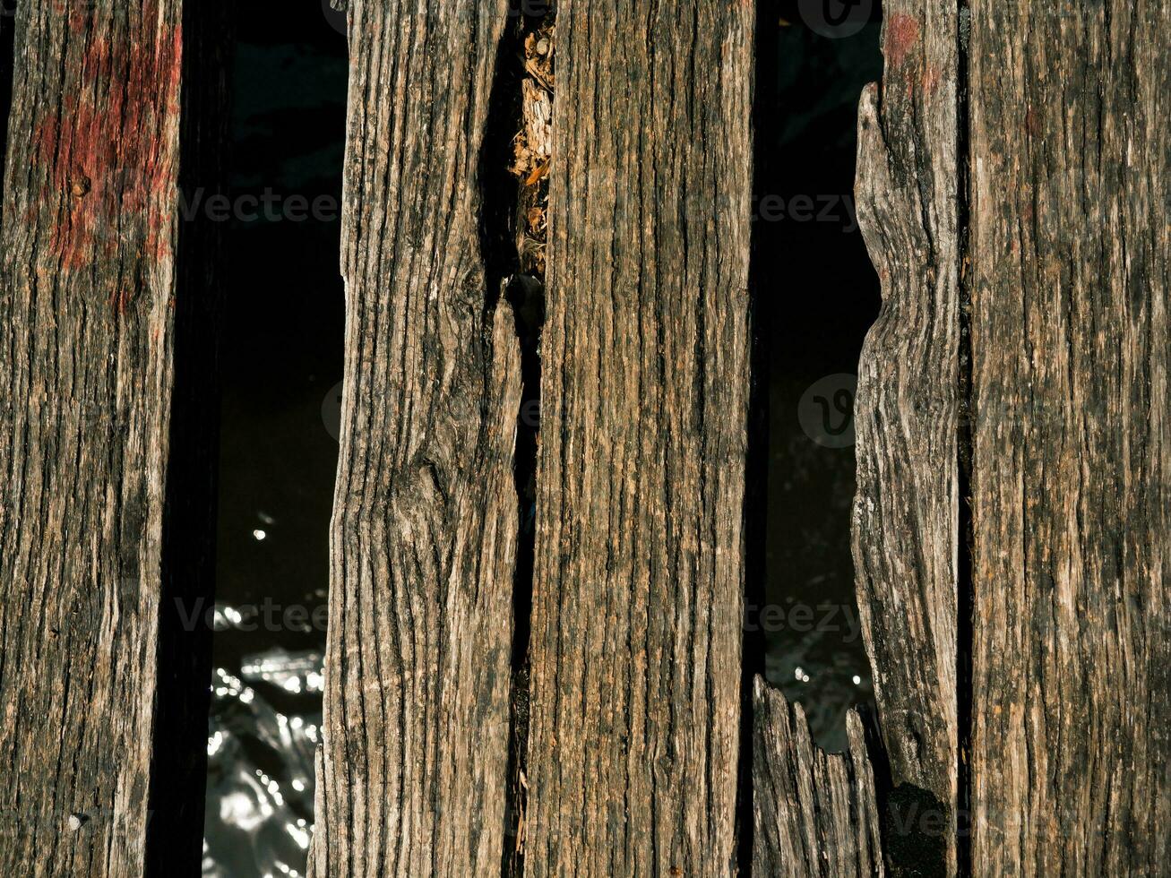 Old worn out and broken wood boards on a bridge over a small river photo