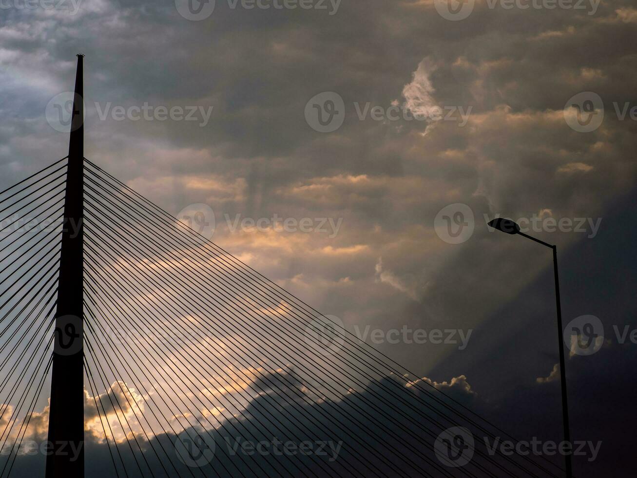 grande torre suspensión puente y poste de luz a nublado puesta de sol foto