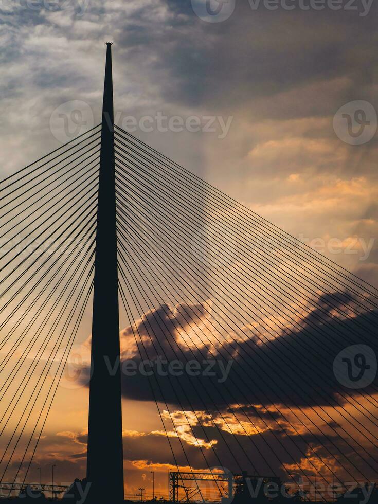 Big suspension bridge tower at sunset - sunrays through the clouds in the background photo