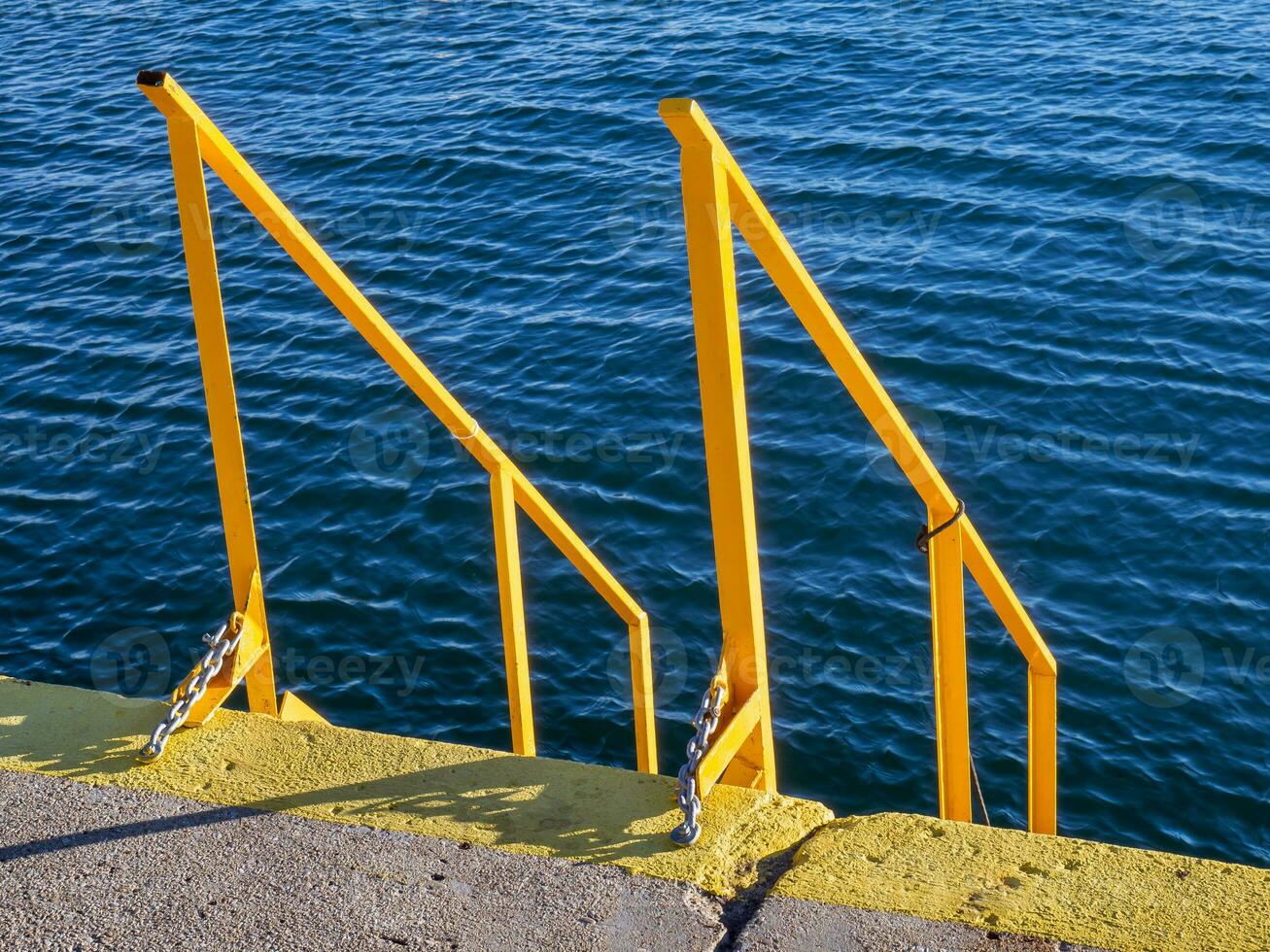Yellow stairs and handrails on the docks - deep blue sea in the background photo