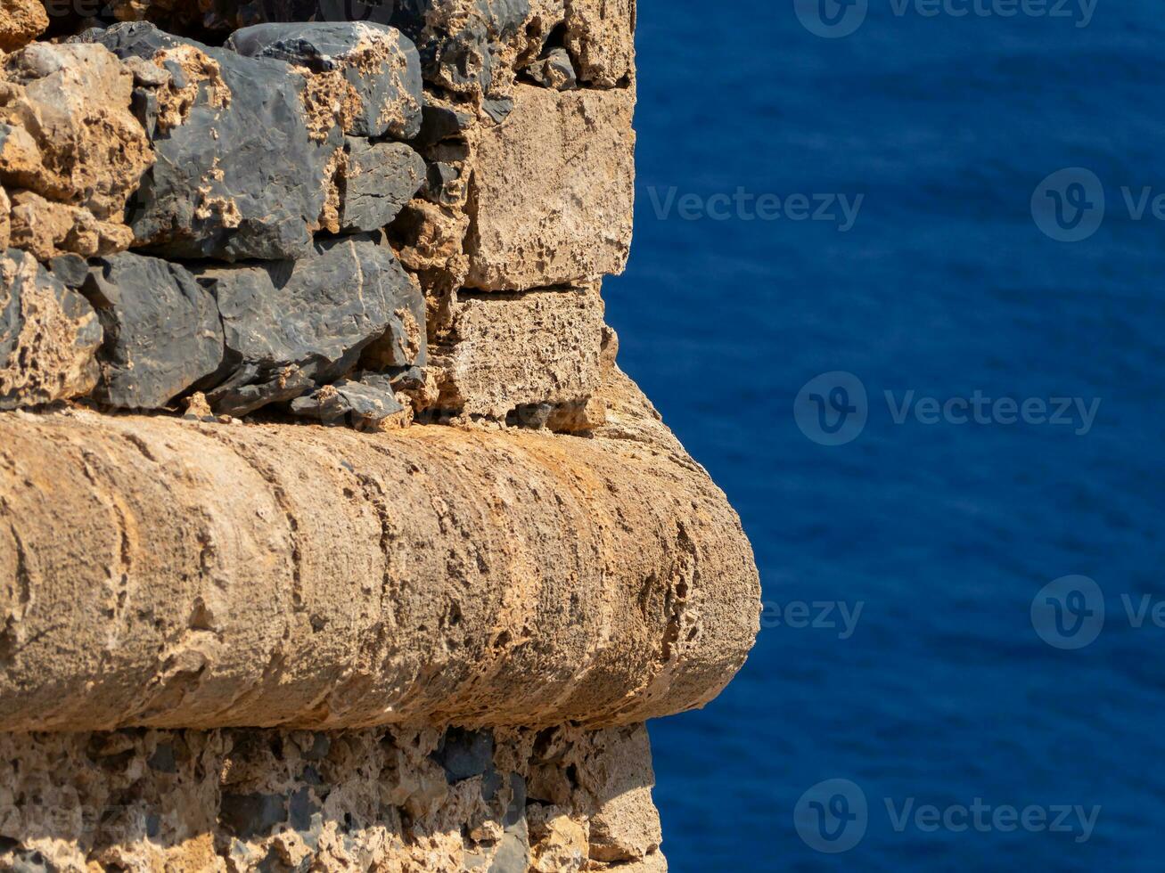 Detail on a medieval fortress stone wall - blue sea in the background photo