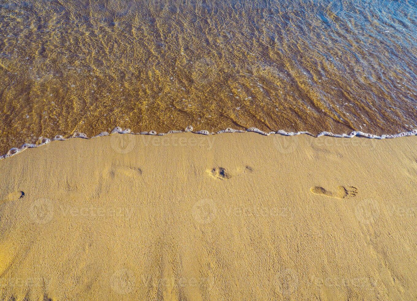 huellas en el arena en un vacío arenoso playa, calma mar foto