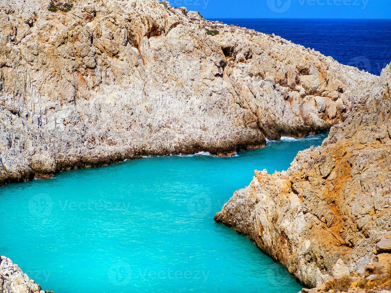 Amazing bright blue water in a secluded cove with orange cliffs surrounding it - Crete, Greece photo