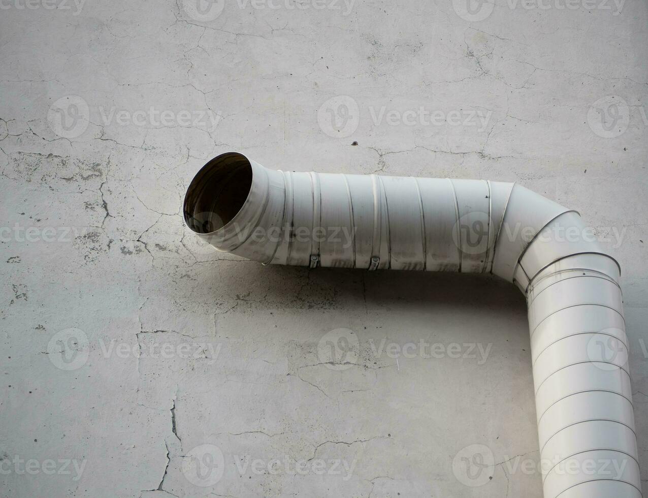 Big white external ventilation pipe up against concrete wall photo