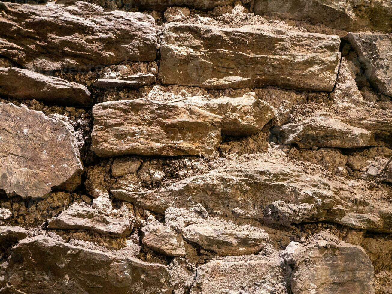 Old stone wall pattern close view background, ancient bricks surface. Natural rock wall photo