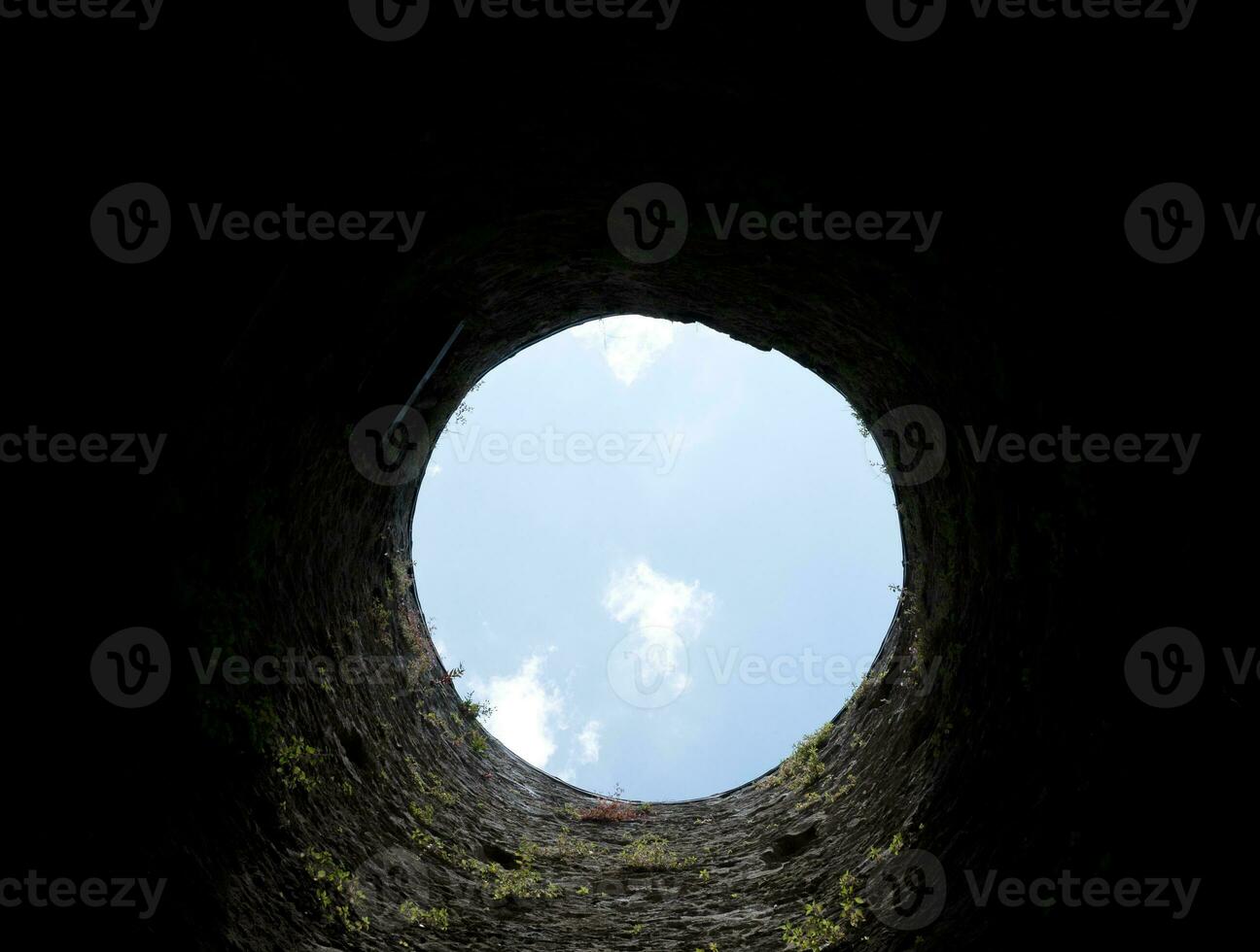 Stone well hole, old construction from inside, brick walls and blue sky background, fall down in the well concept photo