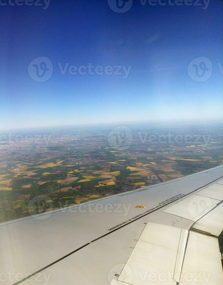 Airplane wing and land far under the plane photo