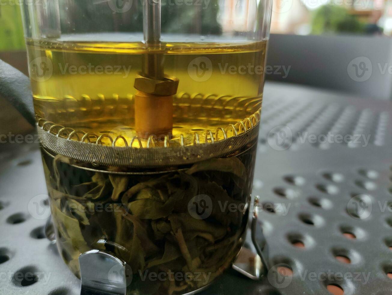 Green tea in a transparent glass kettle photo