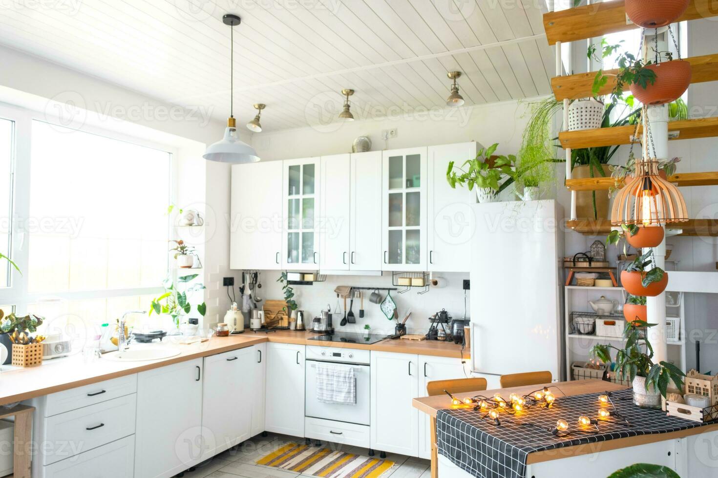 The general plan of a light white modern rustic kitchen with a modular metal staircase decorated with potted plants. Interior of a house with homeplants photo
