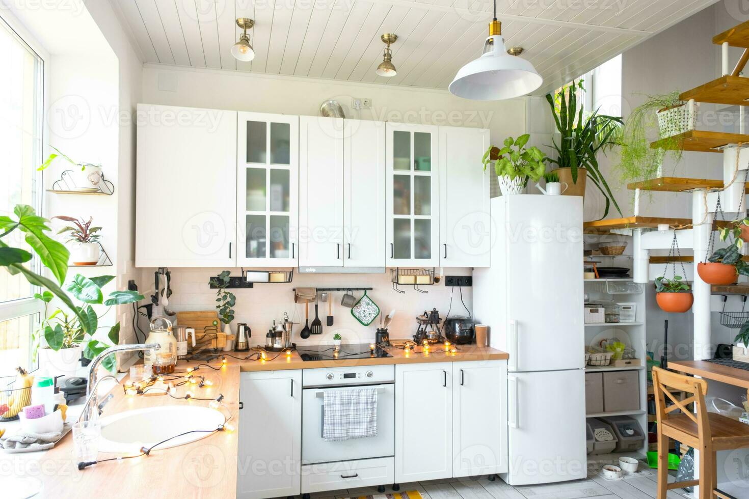 The general plan of a light white modern rustic kitchen with a modular metal staircase decorated with potted plants. Interior of a house with homeplants photo