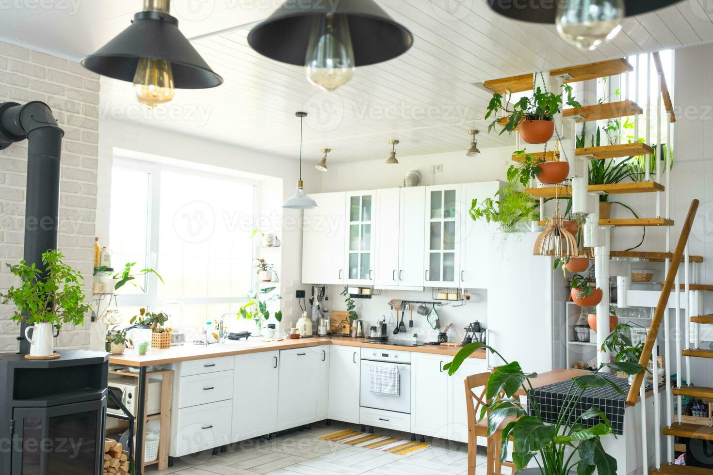 The general plan of a light white modern rustic kitchen with a modular metal staircase decorated with potted plants. Interior of a house with homeplants photo