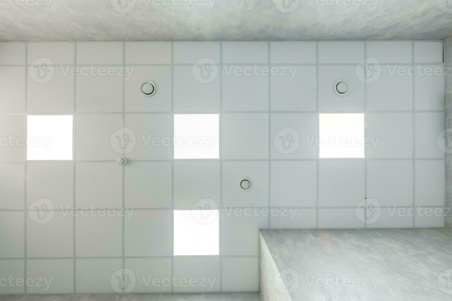 cassette stretched or suspended ceiling with square halogen spots lamps and drywall construction in empty room in house or office. Looking up view photo