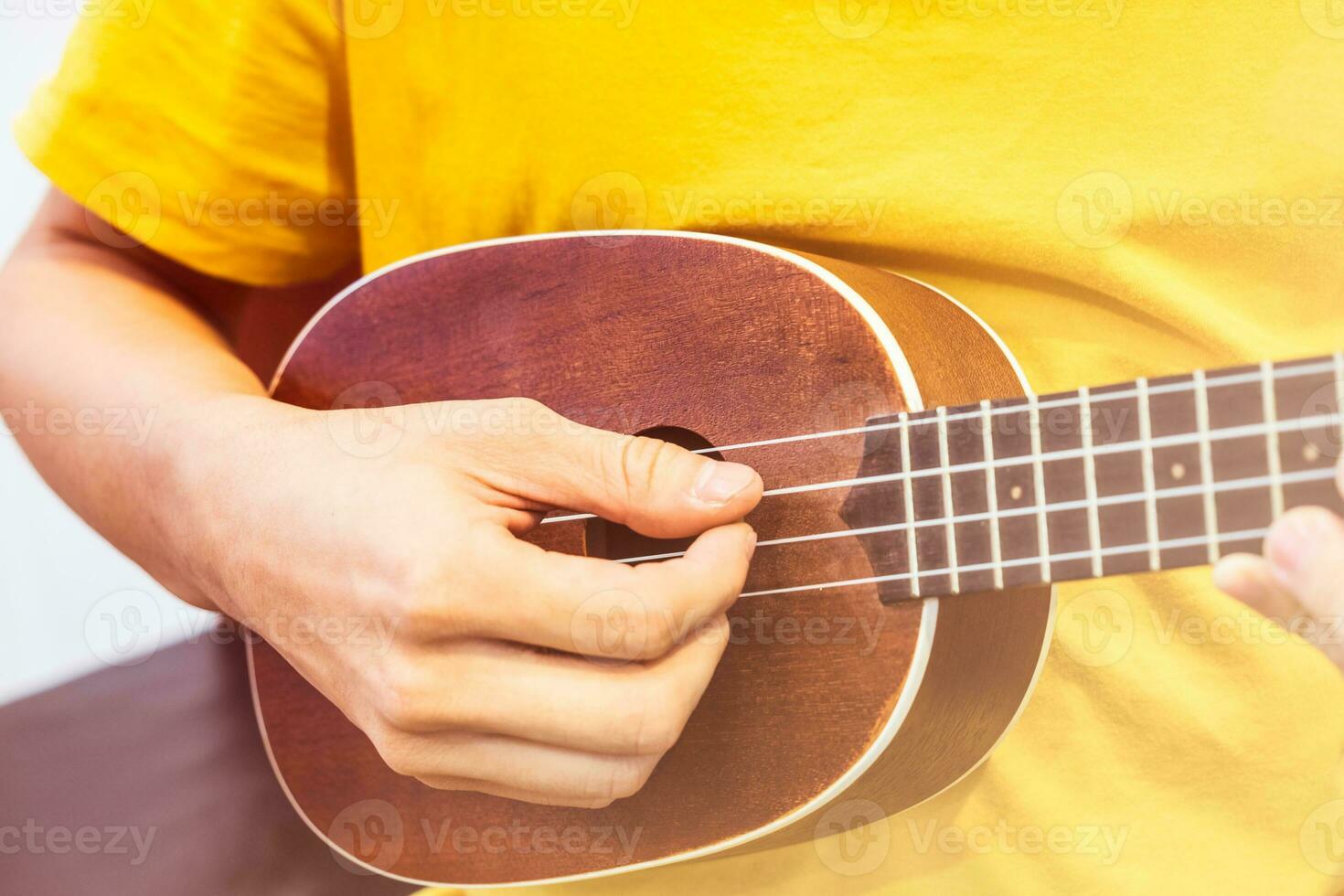 joven jugando de madera ukelele foto