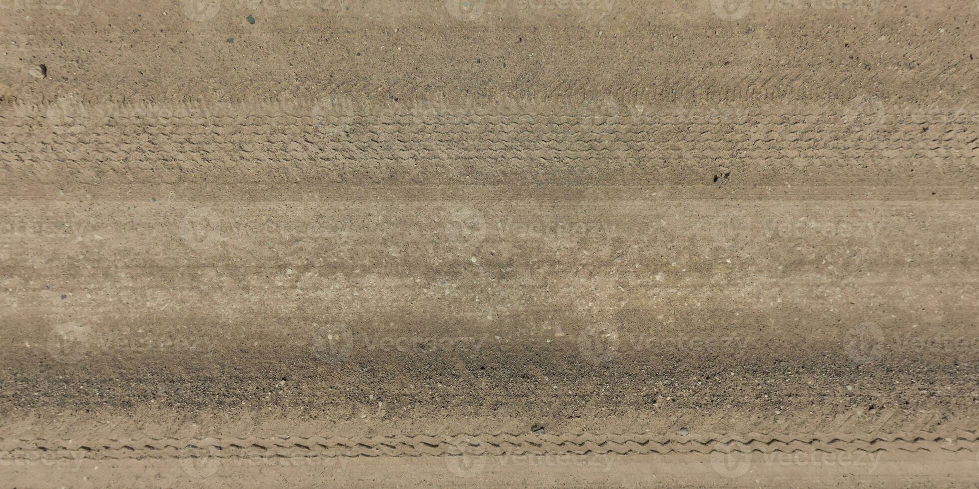 panorama of road from above on surface of gravel road with car tire tracks photo