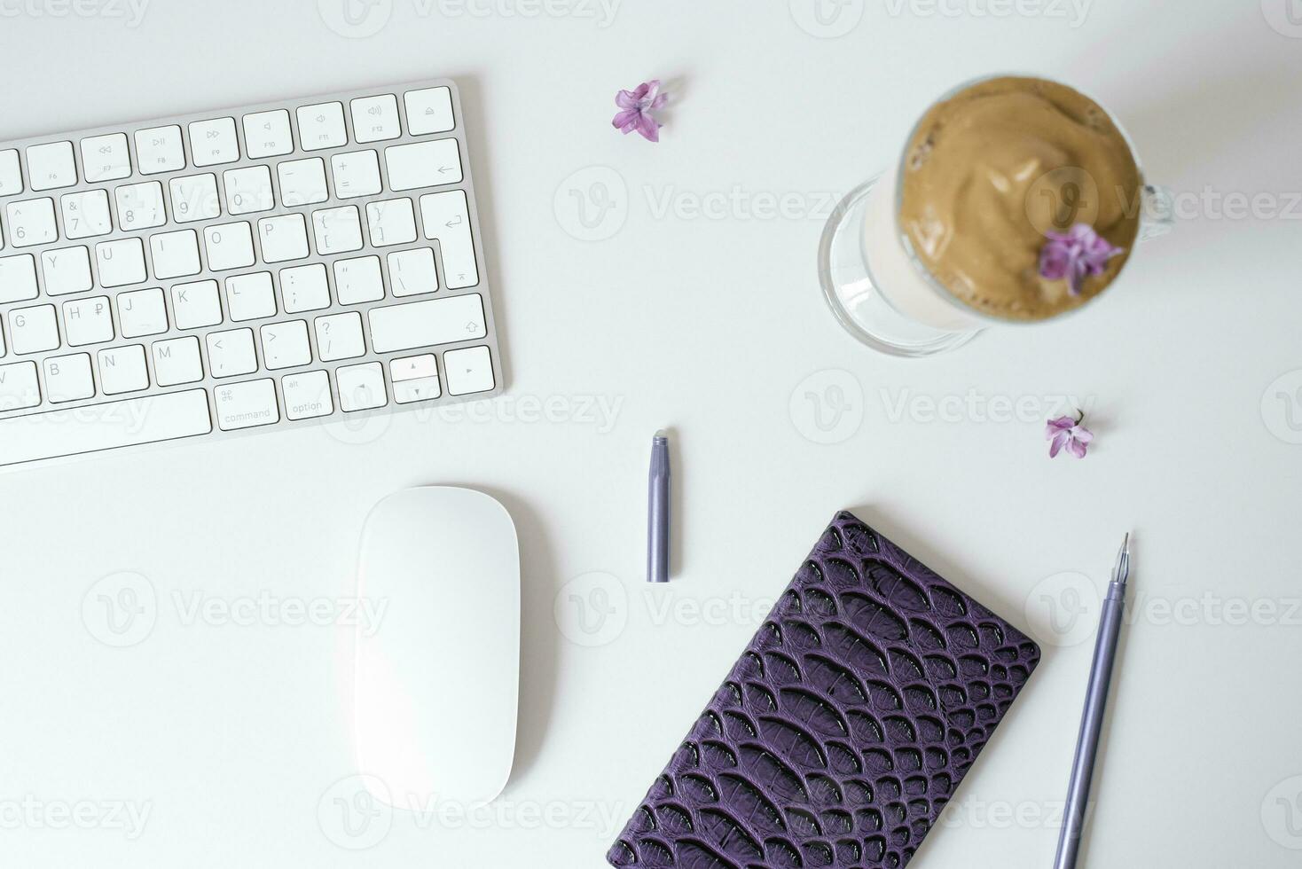 Dalgona coffee in a clear mug, Notepad, pen and computer on the table. Top view. Coffee break at the workplace. photo